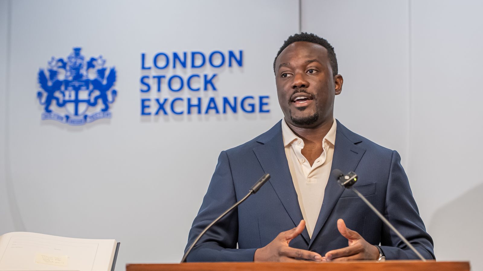 Cecil Adjalo speaking at a lectern at the London Stock Exchange